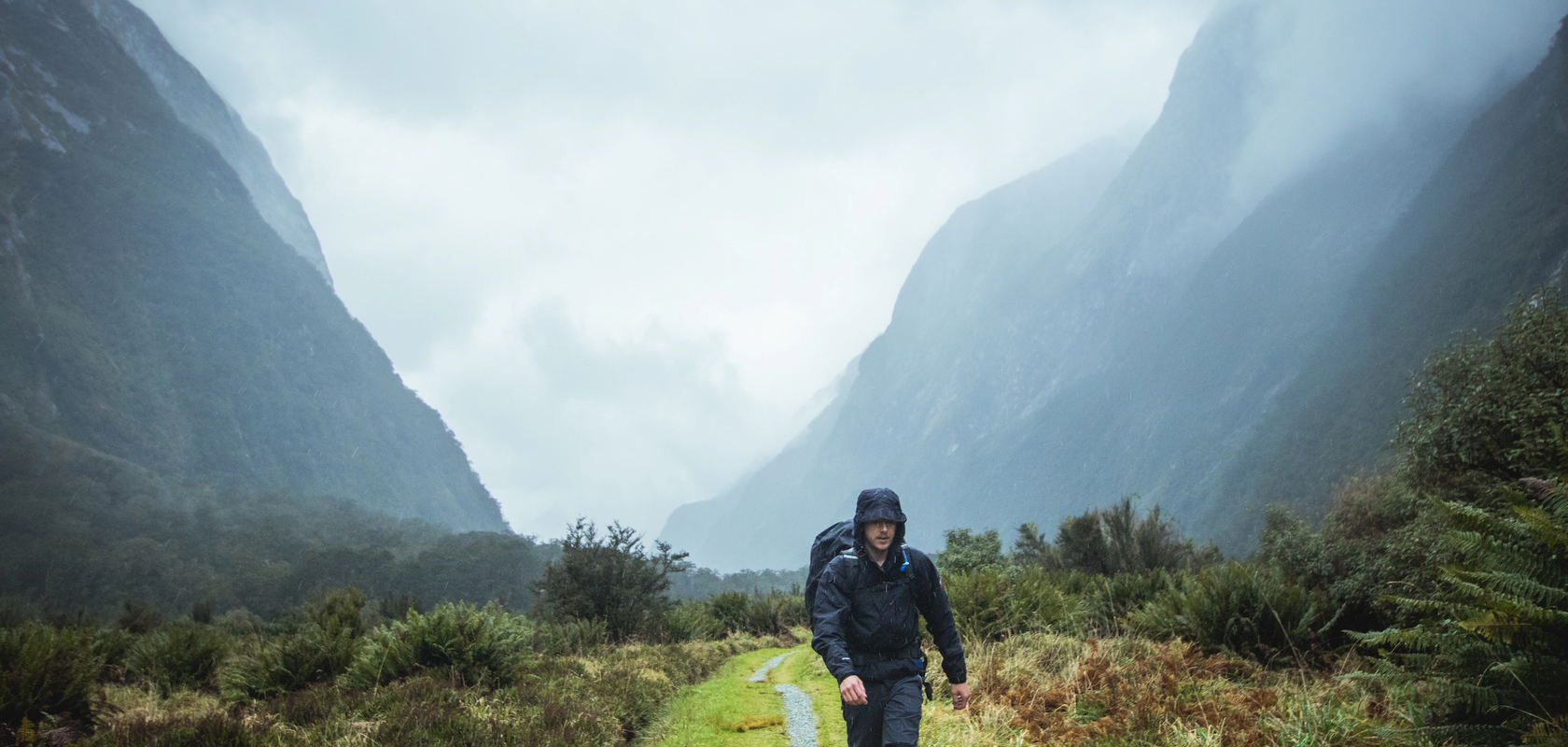 Man hiking through moody skies, Milford Track Winter, Fiordland National Park, New Zealand.webp